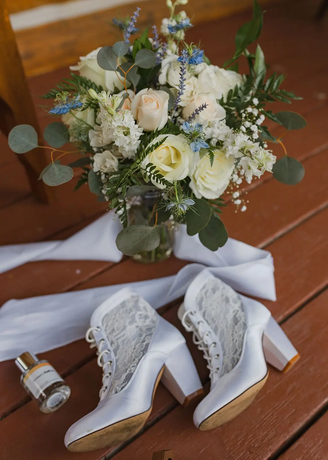 A white bouquet and lace wedding boots on a cabin porch