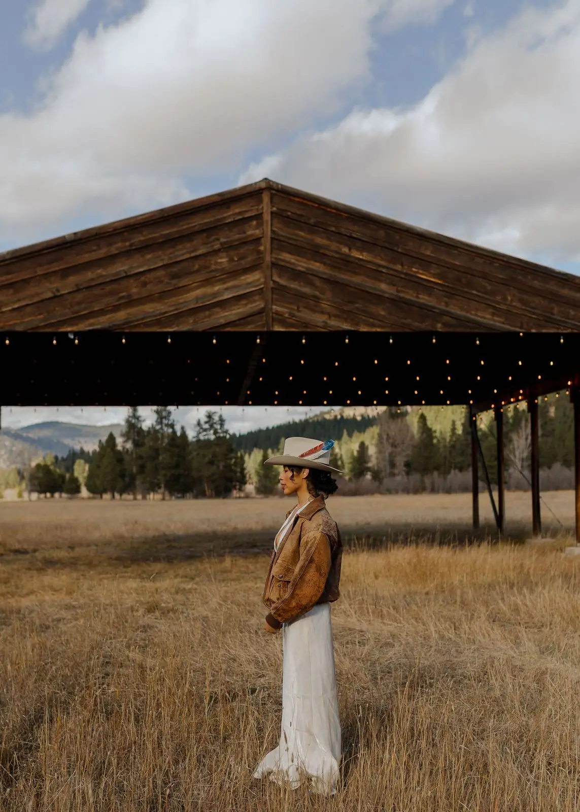 A bride standing in the golden grass beside the hangar