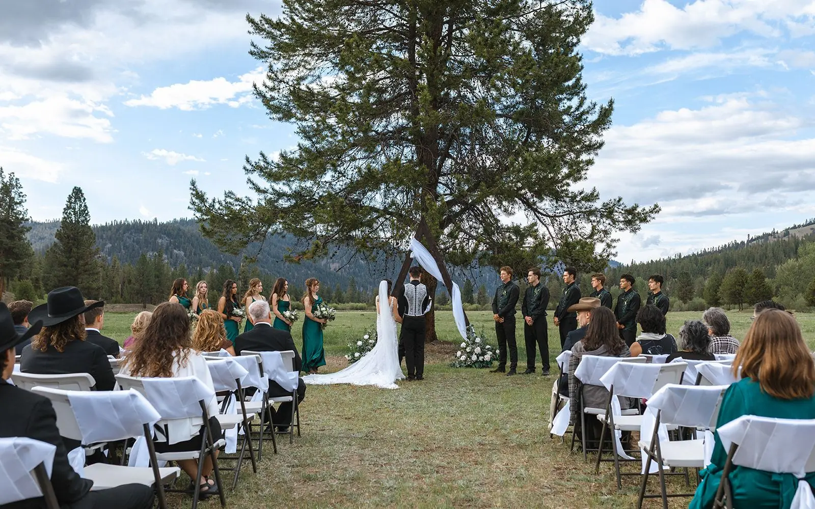 Guests seated for a meadow ceremony with the mountains beyond