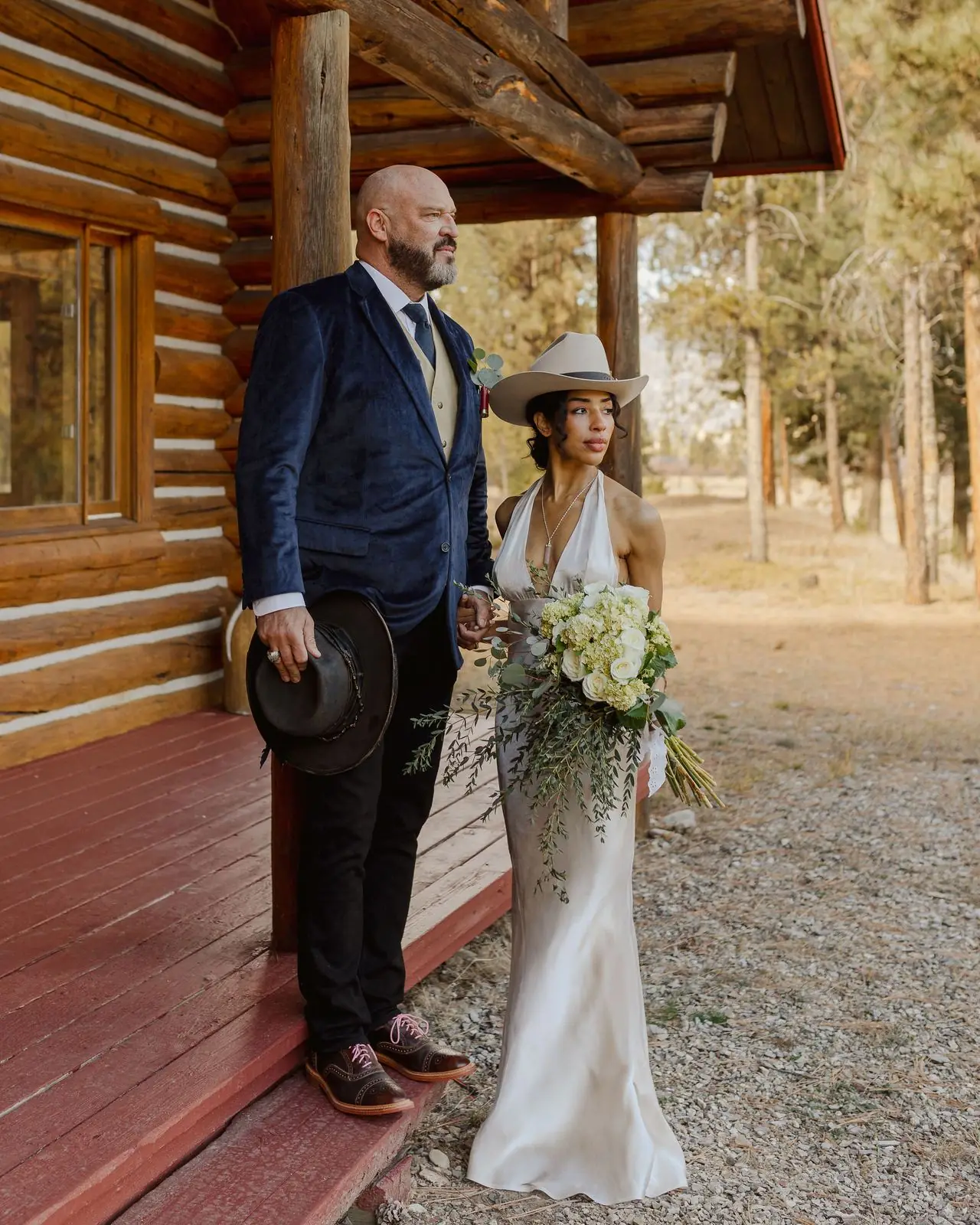 A bride and groom on the porch of a log cabin at Alta Ranch