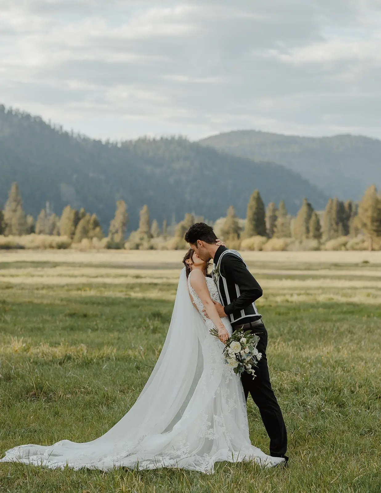 A couple in the green meadow with mountains behind them